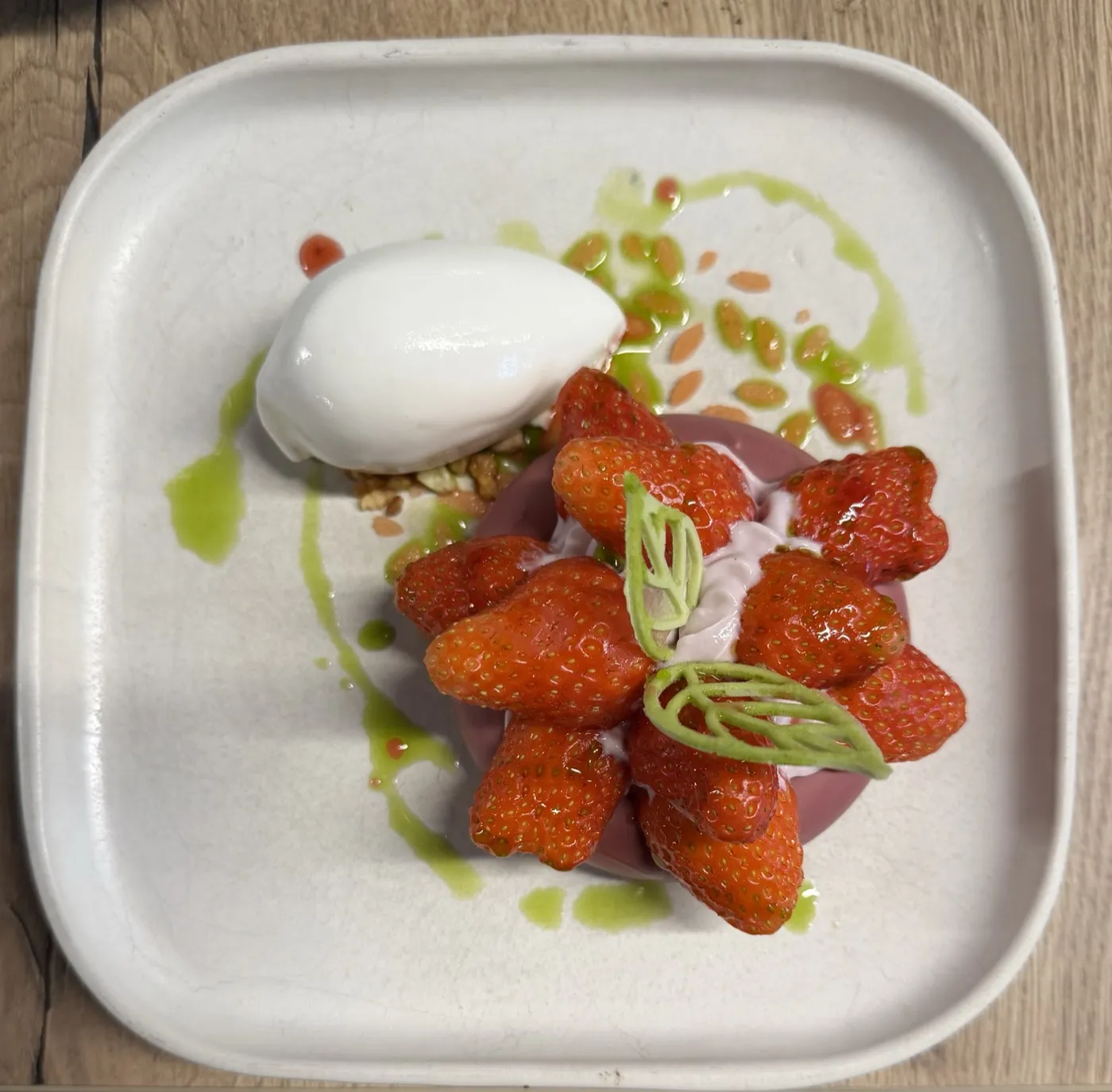 A dessert of ice cream, fresh strawberries and pistachio cream
